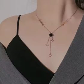 a chic gold clover necklace drapes elegantly on her neckline, adding a sleek and stylish touch to her outfit.