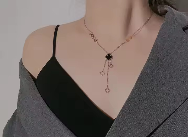 a chic gold clover necklace drapes elegantly on her neckline, adding a sleek and stylish touch to her outfit.